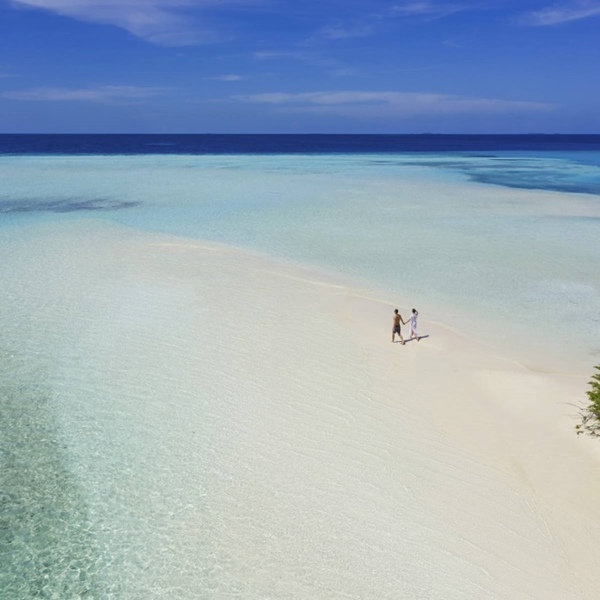 Et par går tur på stranden på Pullman Maamutaa Maldiverne