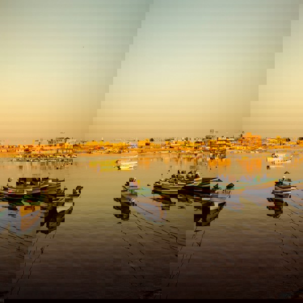 Solnedgang over havnen og både i Salalah, Oman