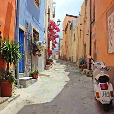 Smal italiensk gade med farvede huse og en vespa