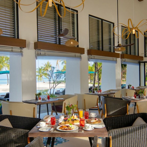 Udsigt til strand, palmer og havet fra en af restauranterne på Pullman Maamutaa Maldiverne